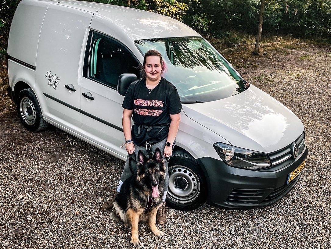Melissa standing beside a white van with Arya sitting at her feet