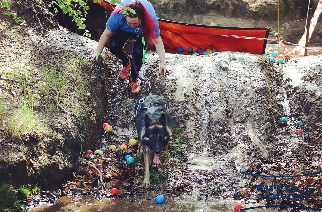 Melissa climbing down a muddy bank while Arya splashes through water filled with coloured balls on an obstacle course