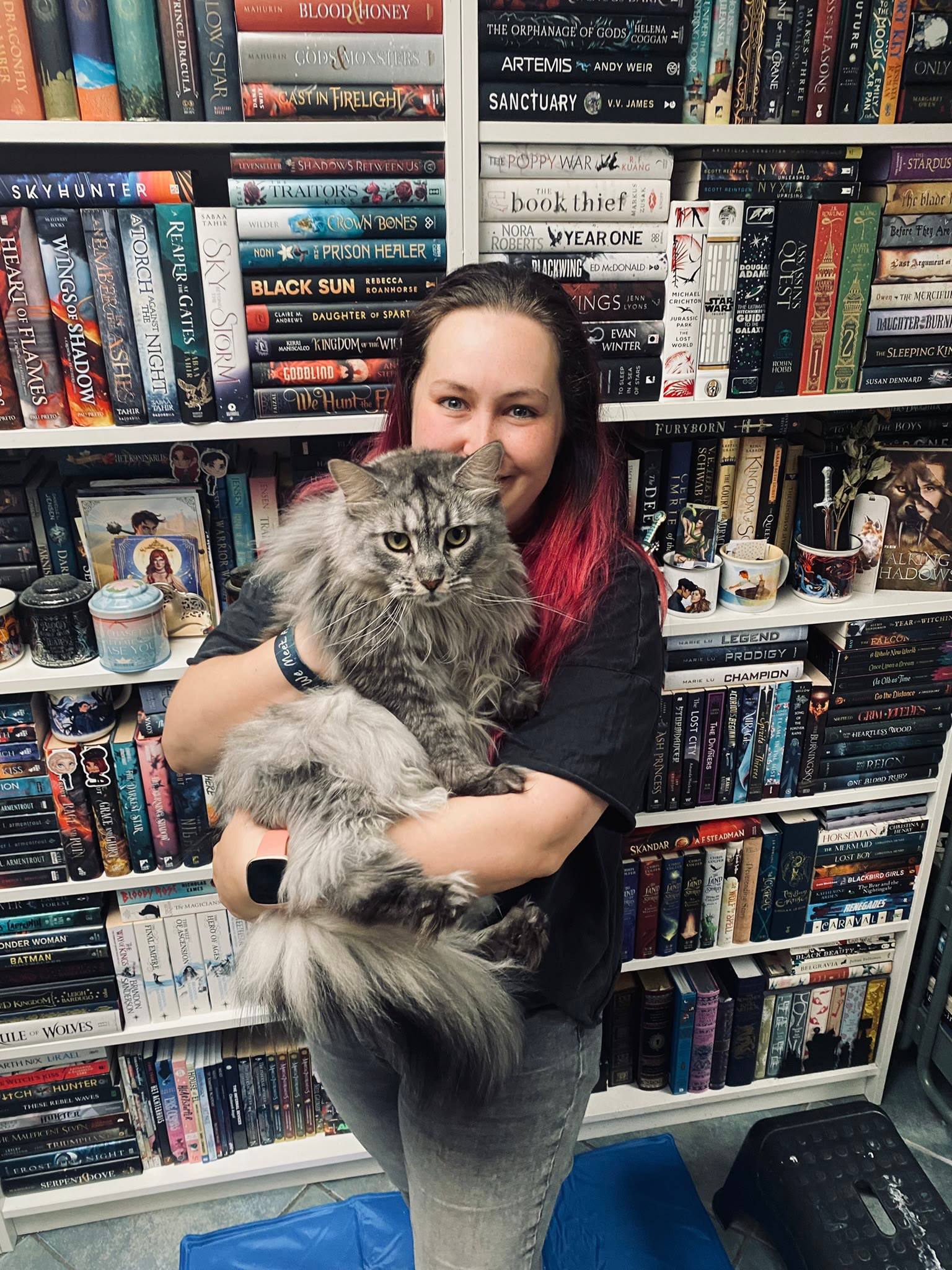 Melissa holding Sansa the Maine Coon in front of her home library